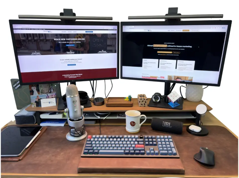 Two monitors sitting on a desk: one monitor has the old website, and the other monitor has the newly redesigned website.